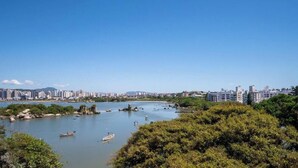 Un río con barcos, rodeado de vegetación y edificios al fondo.