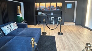 A modern hotel lobby with a blue sofa, a bar area, and a black carpet.