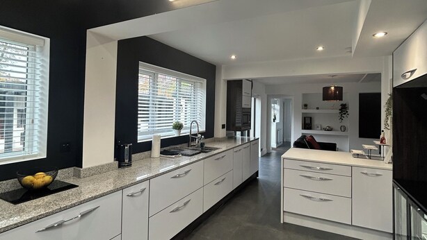 A modern kitchen with a long countertop, built-in appliances, and a skylight.