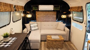 A cozy RV interior with a sectional sofa, a dining table, and a small coffee table.