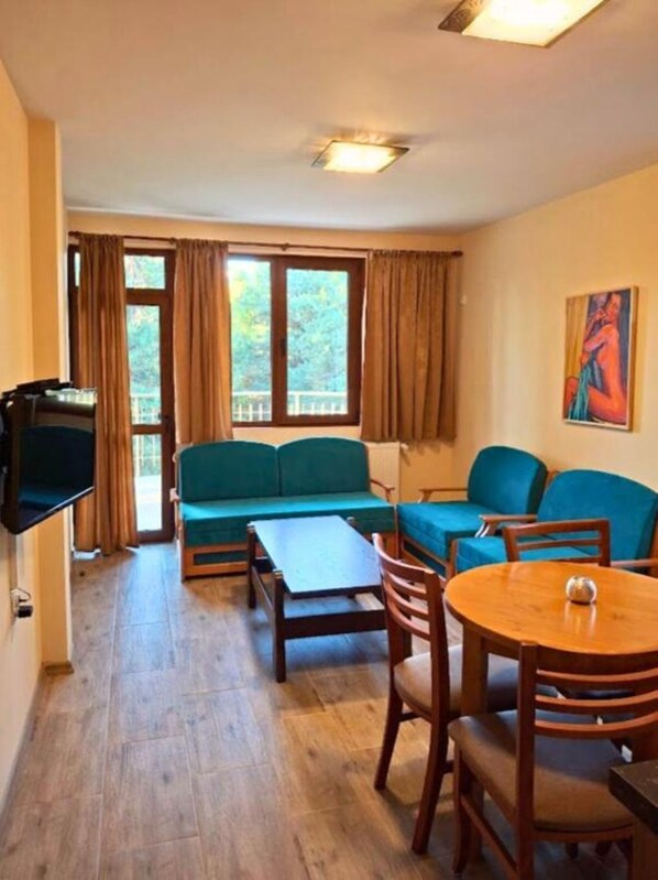 Ein gemütliches Wohnzimmer mit einer Couch, einem Couchtisch und einem an der Wand montierten Fernseher.