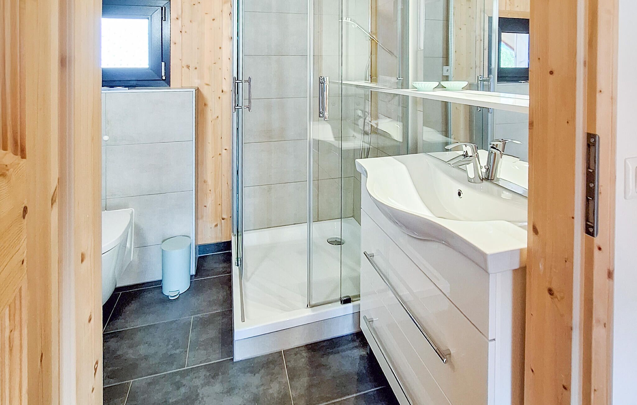 Un baño moderno con cabina de ducha de vidrio, un lavabo blanco y un espejo.