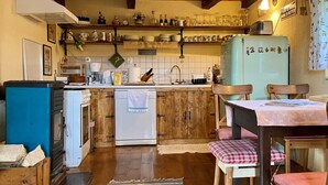 A kitchen with wooden cabinets, a white dishwasher, a blue refrigerator, and a dining area with a table and chairs. - 1 bedroom cozy home in Duga Resa (Duga Resa)