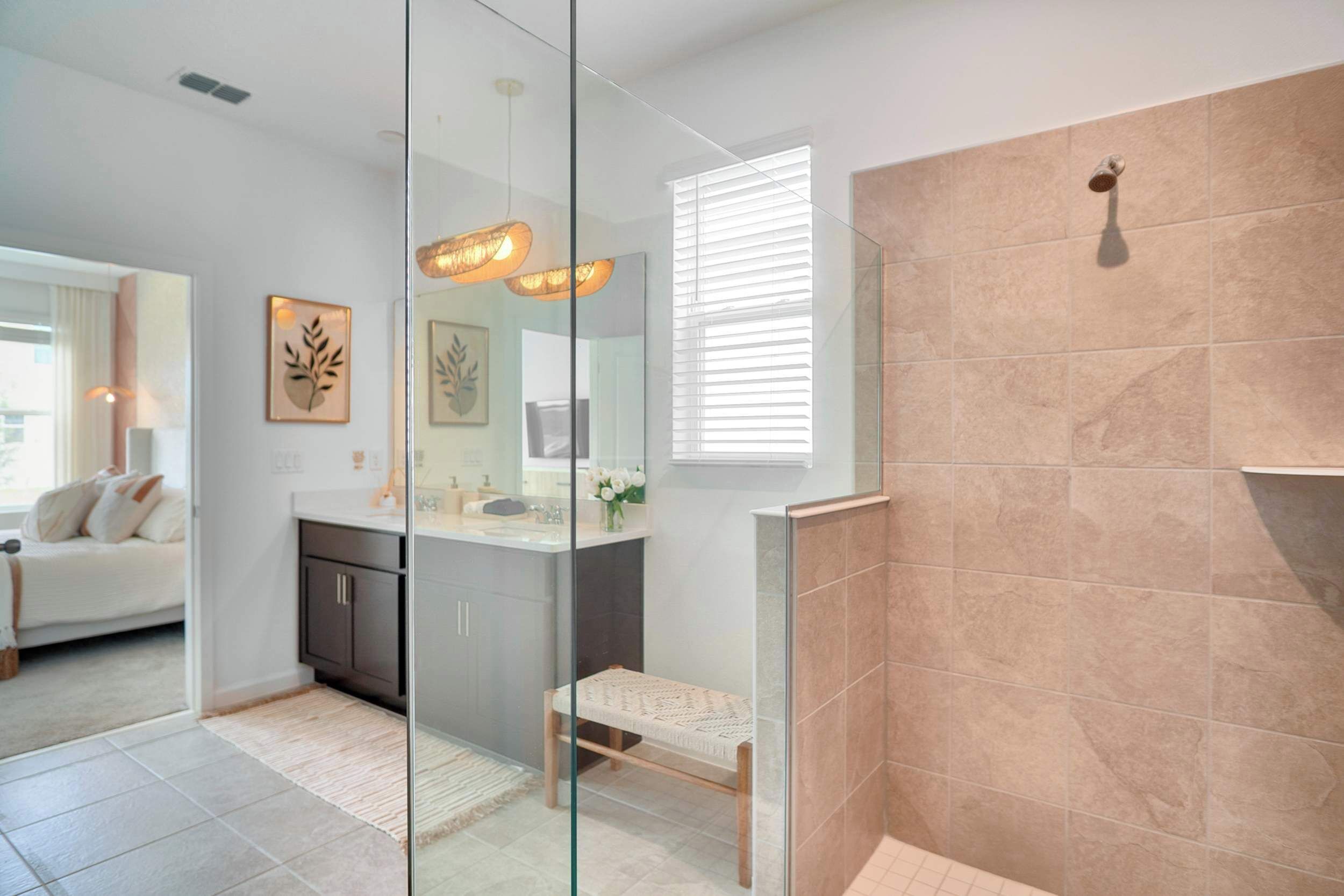 A modern bathroom with a glass shower enclosure, a vanity with a mirror, and a small seating area.