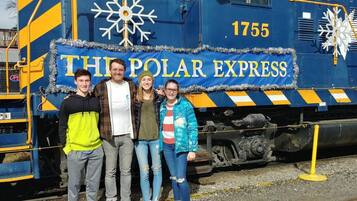 Um grupo de pessoas em frente a um trem com a inscrição 'The Polar Express'.