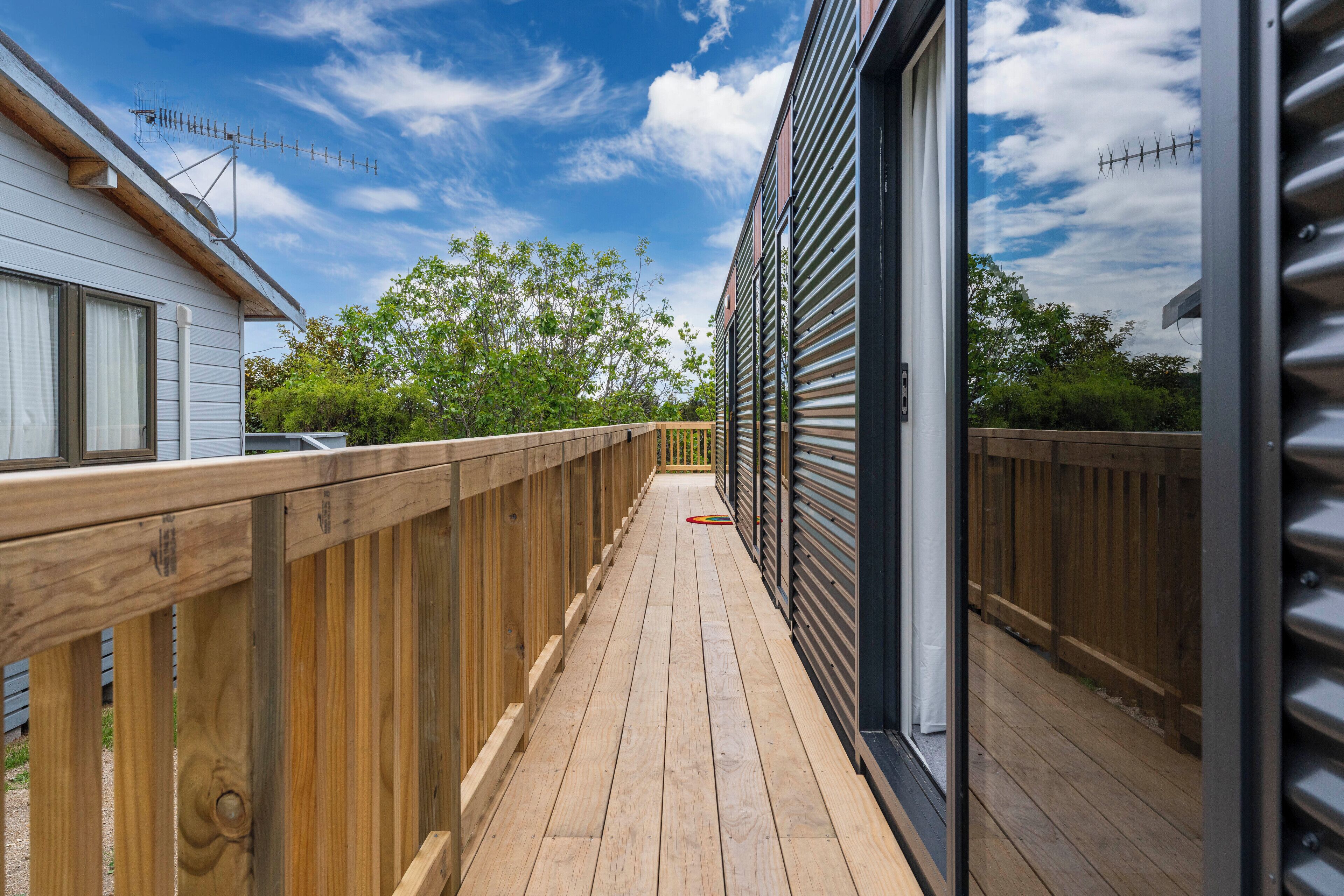 A wooden deck with a view of a house and trees.