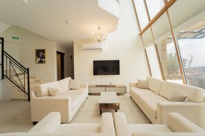 A modern living room with a flat-screen TV, two sofas, a coffee table, and a staircase. - Villa Meltem (Kas)