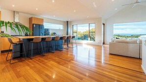 A modern kitchen with a bar area, large windows, and a view of the outdoors. - Sweeping Ocean Views (Torquay)