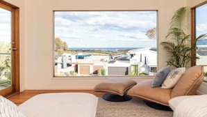 A modern bedroom with a large window, a sofa, and a bed. - Sweeping Ocean Views (Torquay)