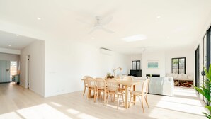 Ein geräumiger Wohnbereich mit Esstisch und Stühlen, Deckenventilator und einem großen Fenster, das für natürliches Licht sorgt.