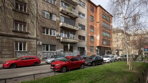 Eine Straße mit geparkten Autos und mehrstöckigen Gebäuden, von denen einige mit Graffiti versehen sind.
