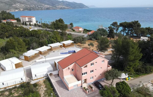 A coastal residential area with a pink building, multiple white structures, and a view of the sea. - Cozy apartment in Orebic with WiFi (Orebic)