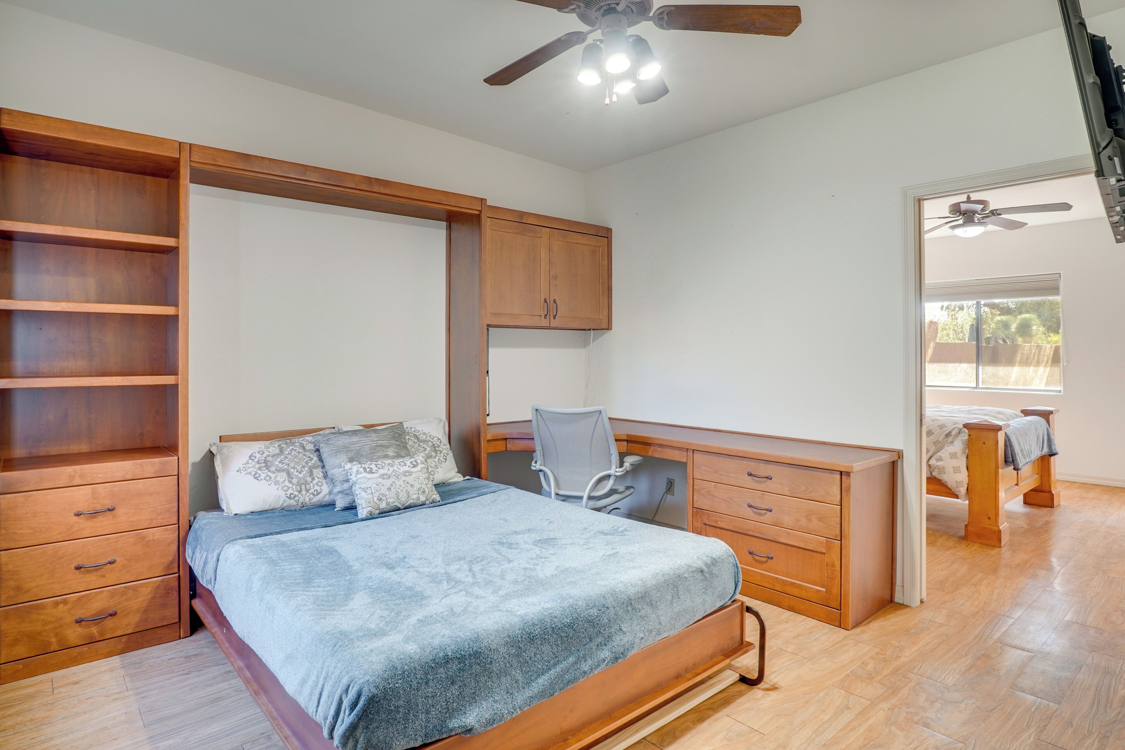 A bedroom with a bed, desk, chair, and built-in shelving.