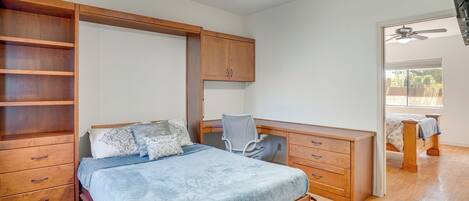 A bedroom with a bed, desk, chair, and built-in shelving.