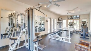 A gym with various exercise machines, mirrors, ceiling fans, and a large window. - Mtn-View Tucson Home Near Hiking & Biking (Tucson)