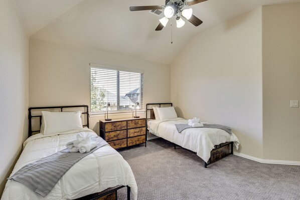 A bedroom with two beds, a dresser, a ceiling fan, and a window with blinds. - 3,000-Sq-Ft Family Home in Anna w/ Game Room! (Anna)