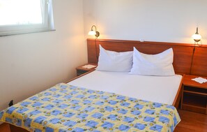 Ein ordentlich bezogenes Bett mit einer floralen Steppdecke, zwei Nachttischlampen und einem hölzernen Kopfteil.
