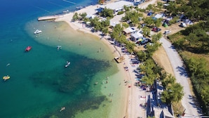 Vista aérea de una zona costera con aguas cristalinas, barcos e instalaciones de camping.
