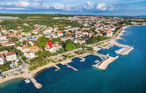 Vista aérea de un pueblo costero con edificios residenciales, un puerto deportivo y una playa.