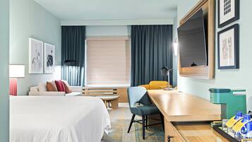 A hotel room with a bed, a desk, a chair, a small table, a bench, a sofa, and a window with curtains.