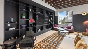 A modern living room with a large bookshelf, a sofa, a coffee table, and a patterned rug.