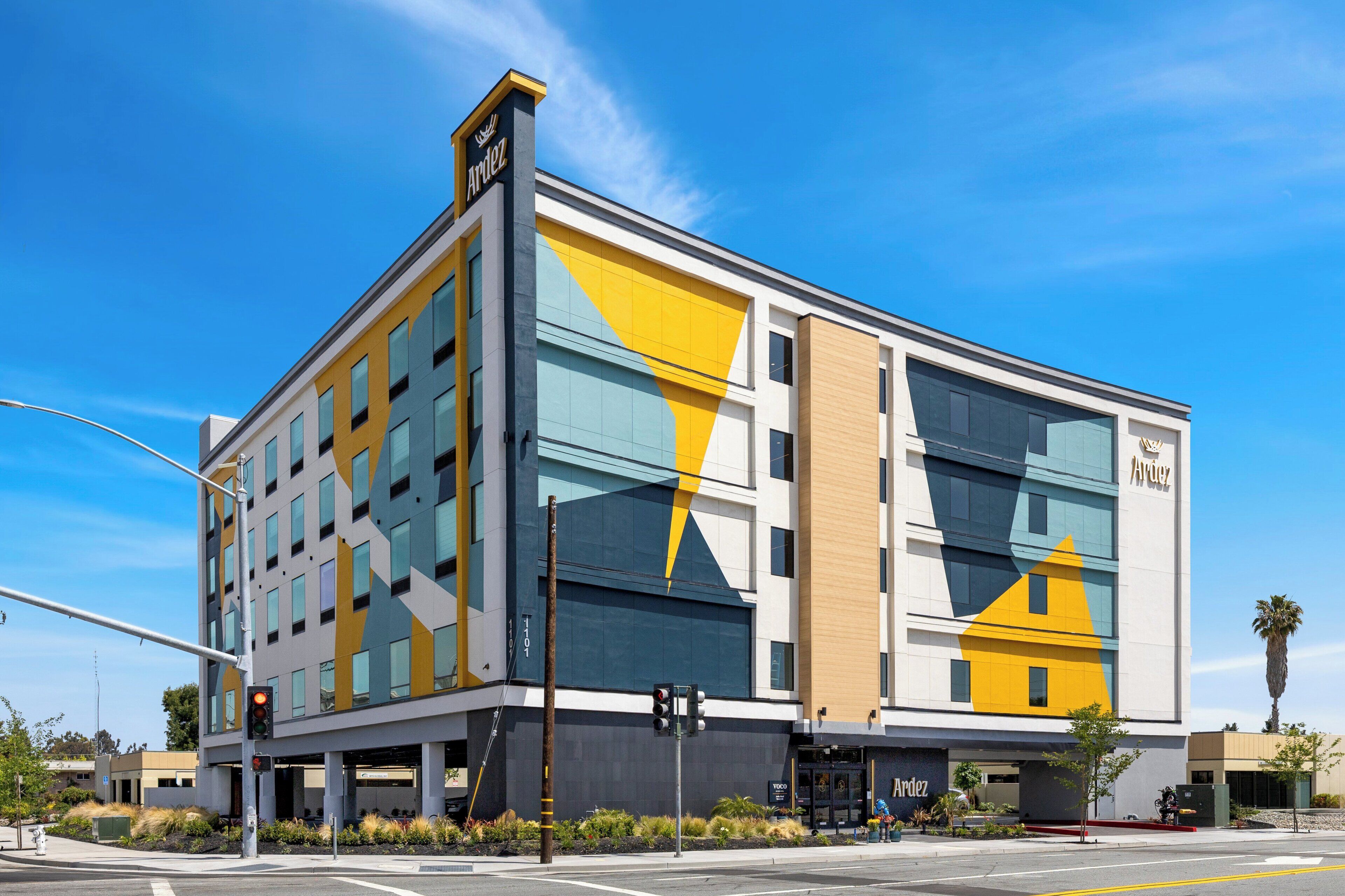 Ein modernes Hotel mit einer geometrischen Fassade, großen Fenstern und einem markanten Logo.