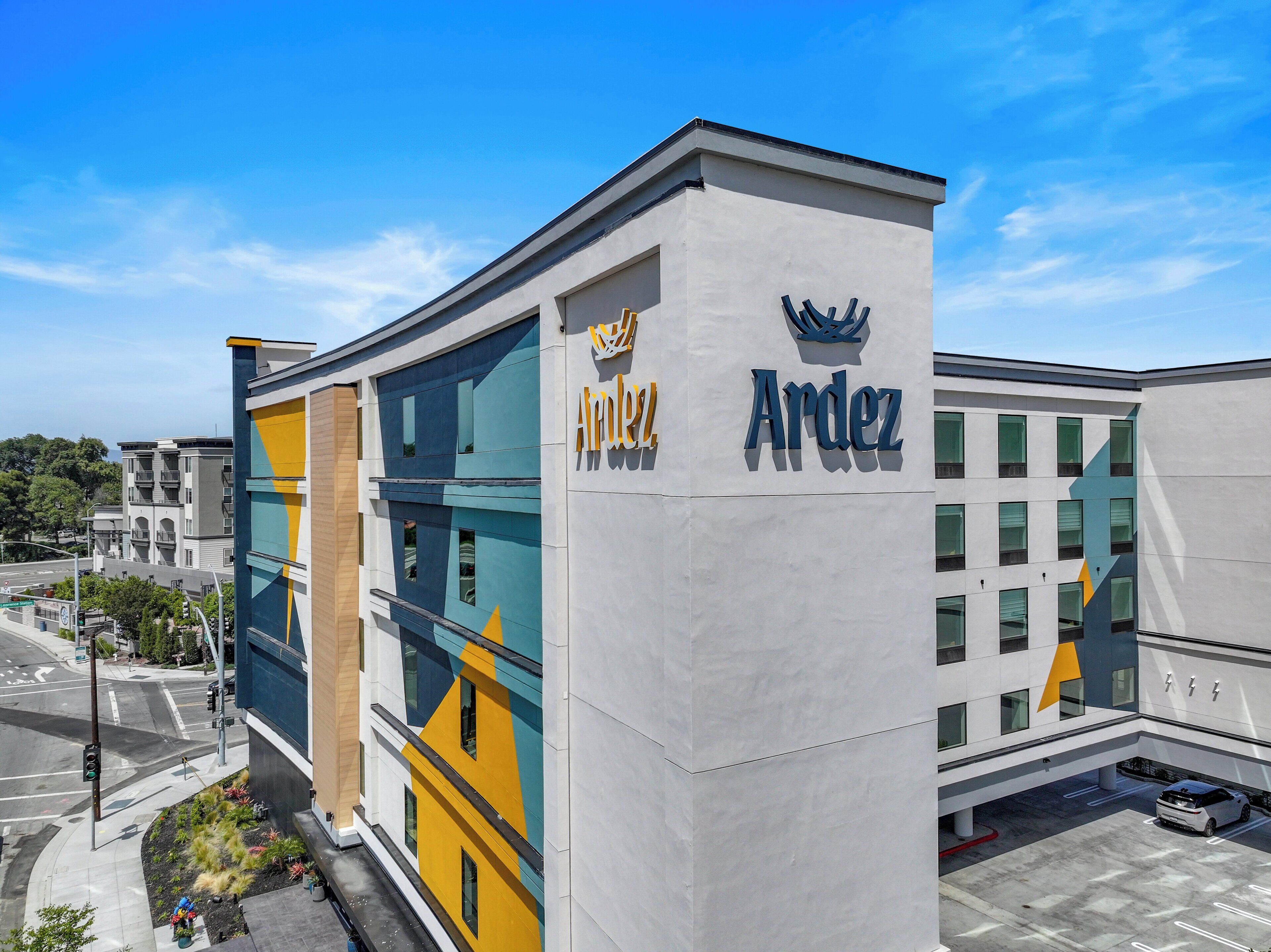 Un bâtiment moderne avec une enseigne « Ardez », un parking et une vue sur la rue.