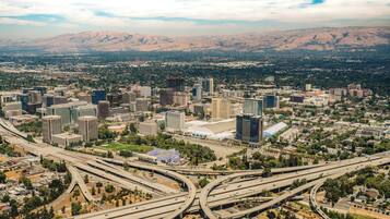 An aerial view of a city with multiple highways, buildings, and mountains in the background.