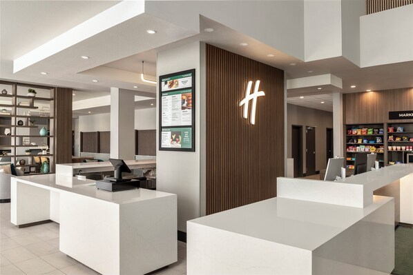 A modern hotel lobby with a reception desk, a menu board, and a children's snack area. - Holiday Inn Hotel And Suites Commerce City Denver Airport By Ihg (Commerce City)