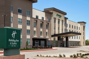 A Holiday Inn & Suites by IHG building with a covered entrance and outdoor seating area. - Holiday Inn Hotel And Suites Commerce City Denver Airport By Ihg (Commerce City)