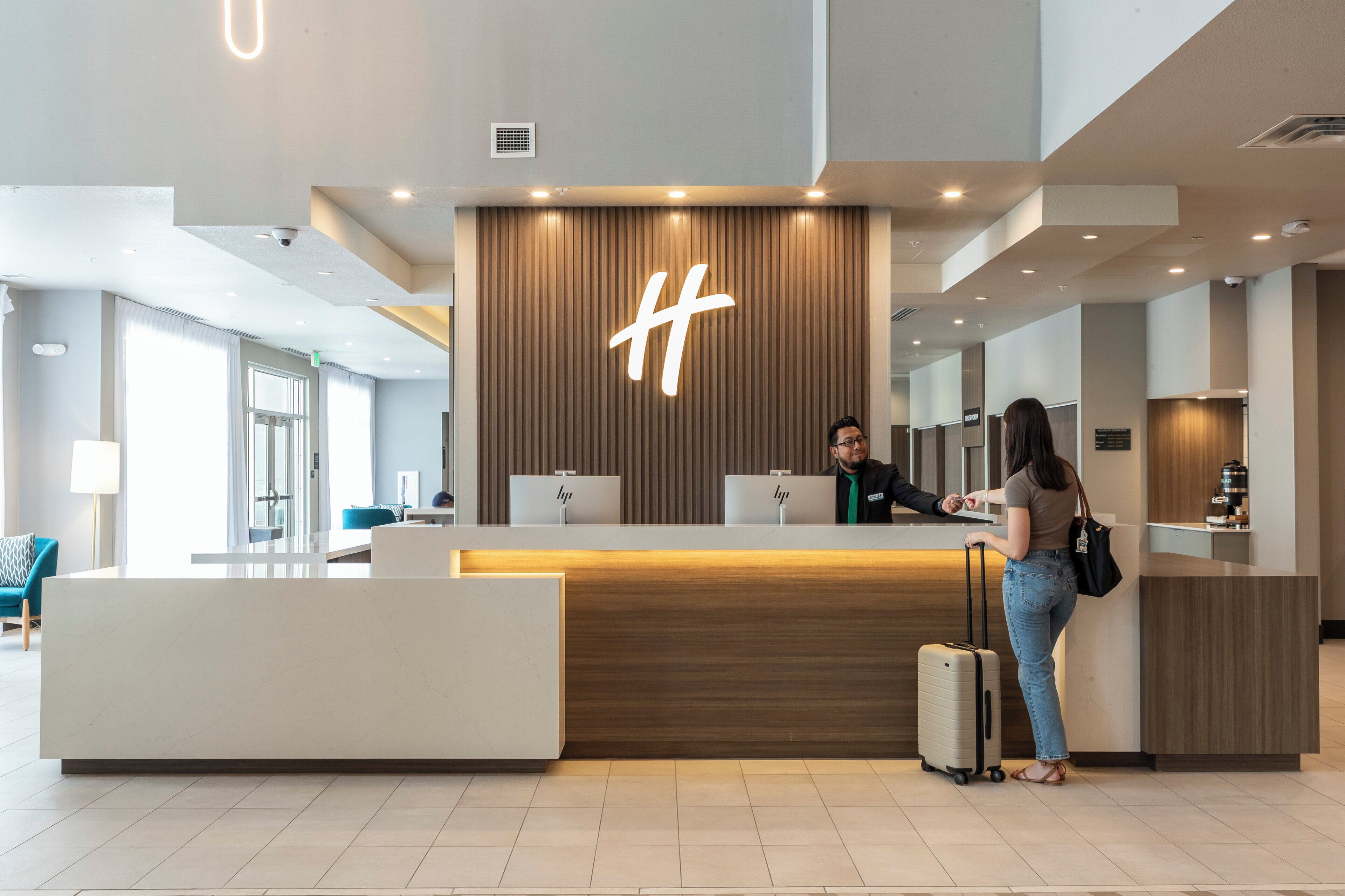 A hotel reception desk with a modern design, a large illuminated logo, and a check-in counter.