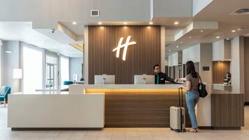 A hotel reception desk with a modern design, a large illuminated logo, and a check-in counter.