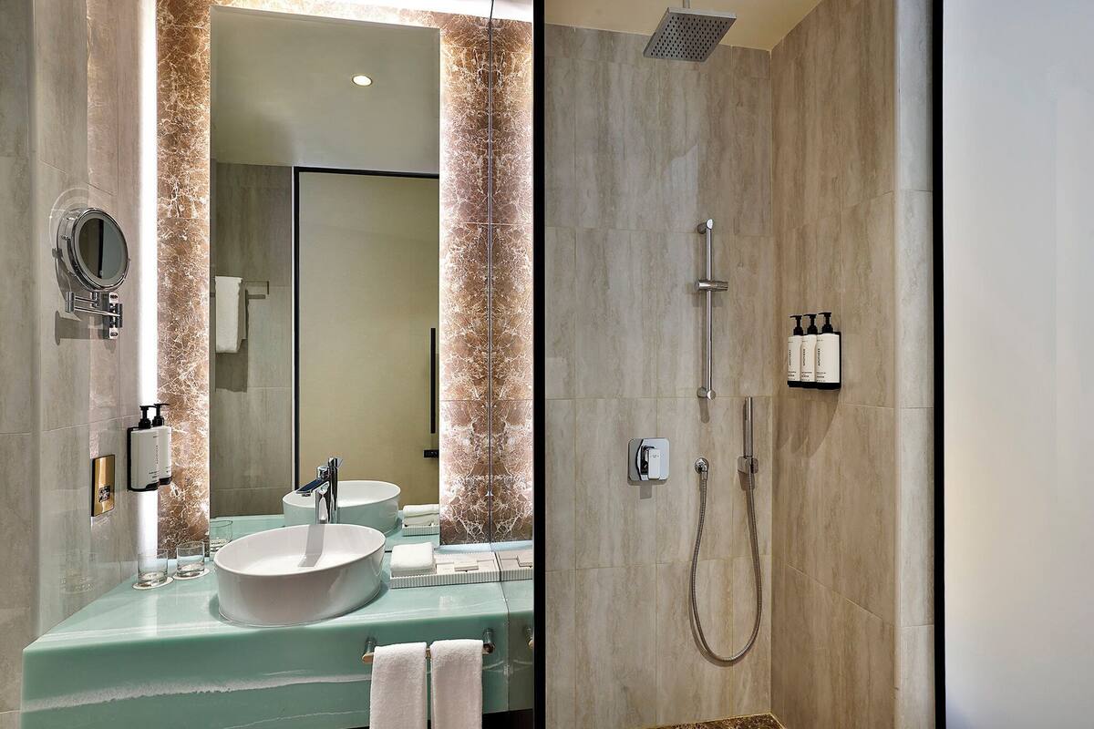 A bathroom with a sink, mirror, and shower.