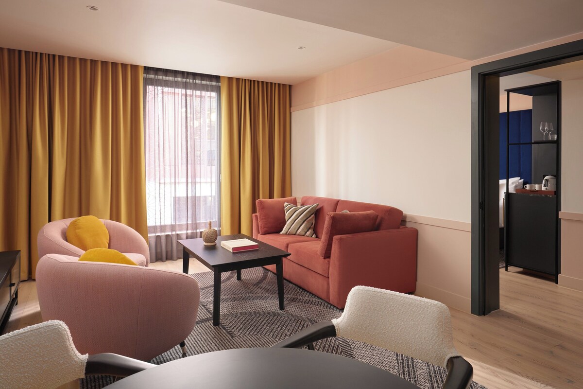 Una sala de estar moderna con un sofá, un sillón y una mesa de comedor.