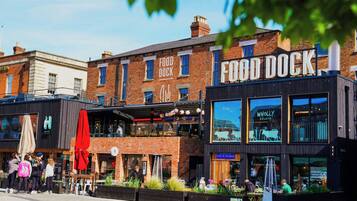 Una calle con una hilera de edificios, incluyendo un restaurante llamado 'Food Dock' y otro con un letrero que dice 'Café & Kitchen'.