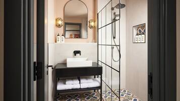 Un baño moderno con tocador negro, un espejo grande, cabina de ducha y baldosas de suelo estampadas.