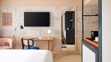 A modern hotel room with a bed, desk, chair, and a large mirror.