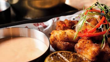 A meal with breaded and fried food, a lemon slice, and a dipping sauce.