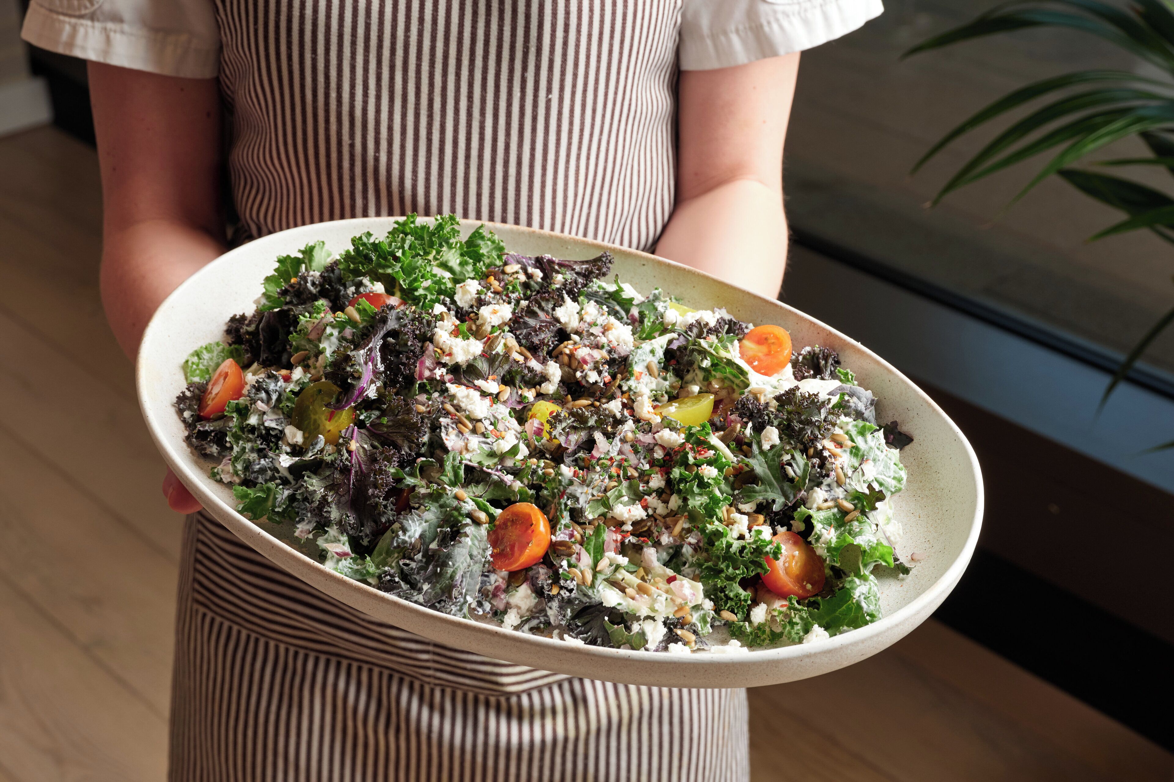 A person holding a large bowl of salad.