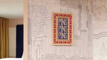 Paret amb un dibuix geomètric i un quadre amb la inscripció 'PINS PINS PINS'.