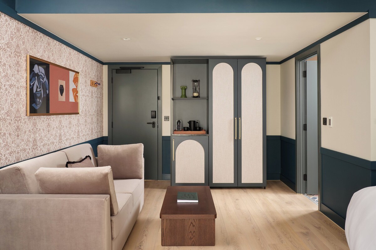 Una habitación moderna con sofá, una mesita de madera y un armario con espejo.