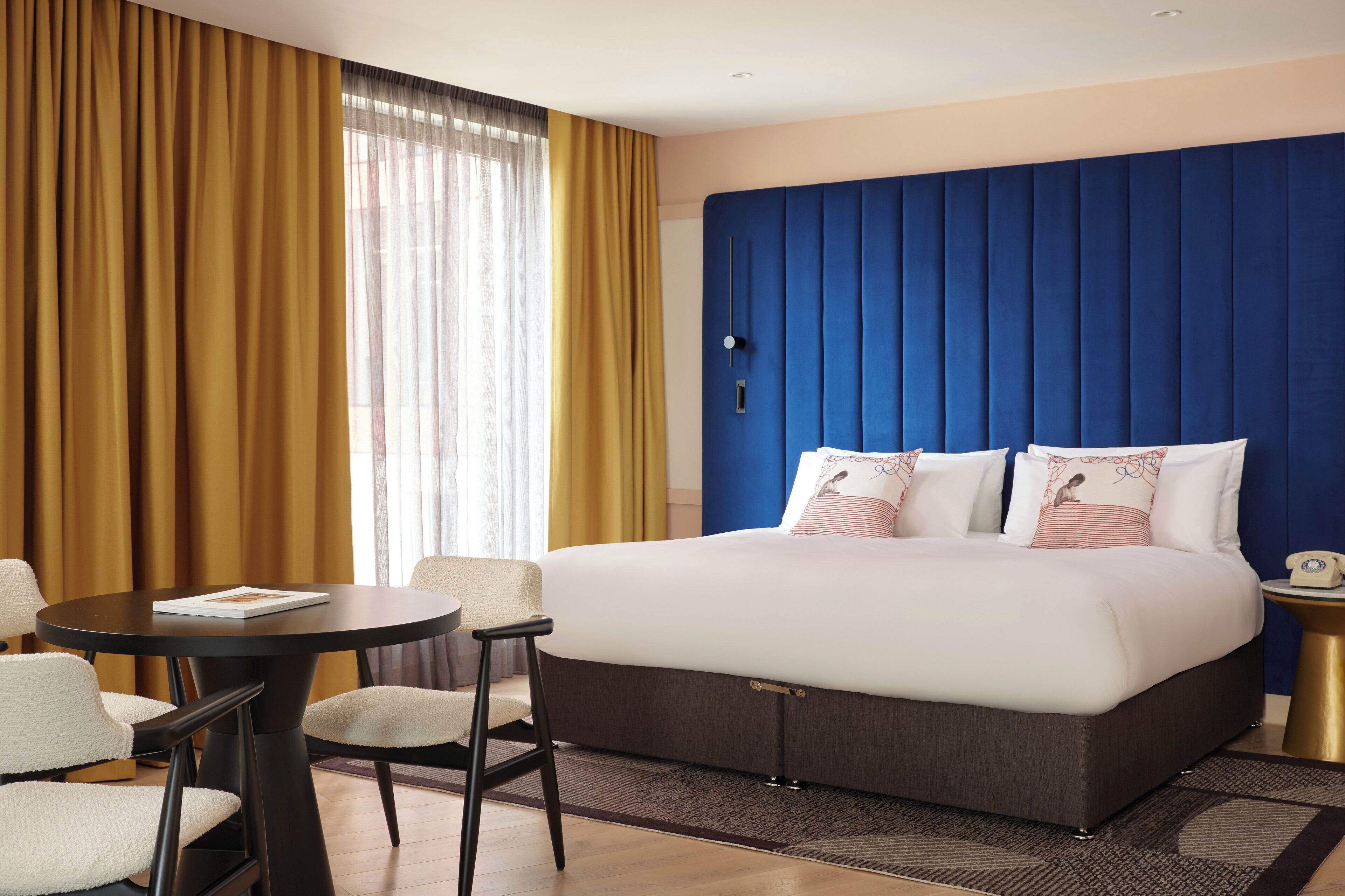 Camera d'albergo con un letto grande, un tavolino rotondo e due sedie.