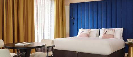 Camera d'albergo con un letto grande, un tavolino rotondo e due sedie.