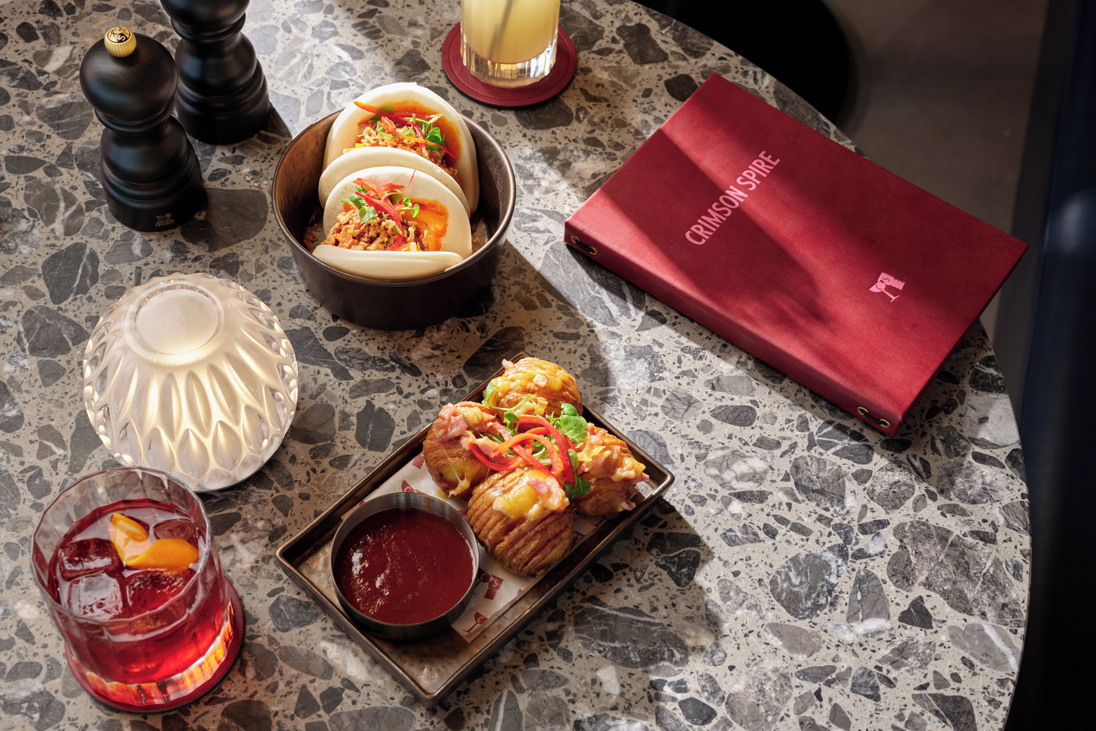 Una mesa con comida, bebida, salsas y un menú.