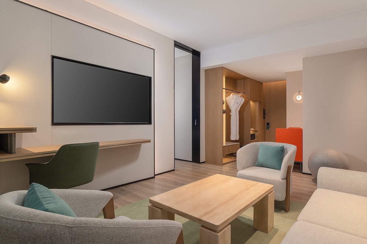 A modern living room with a sofa, chairs, a coffee table, and a TV.