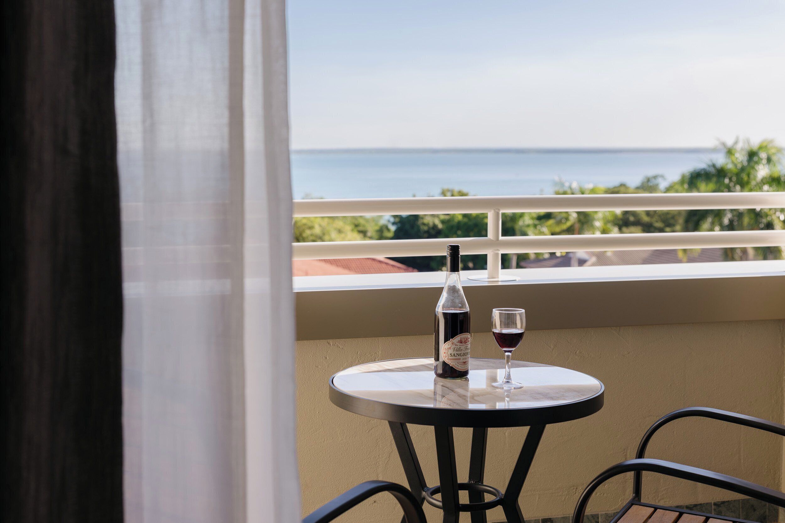 A balcony with a table, a bottle of wine, and a glass of wine.