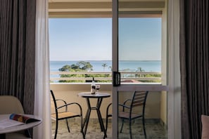 A balcony with a table and chairs, a bottle of wine, and a glass. - voco Darwin Suites by IHG (Darwin)