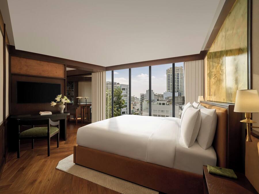 Habitación de hotel con una cama grande, un escritorio, un televisor y vistas de la ciudad.