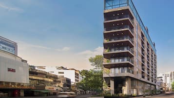 A multi-story hotel with a modern design, featuring balconies on each floor and large windows.