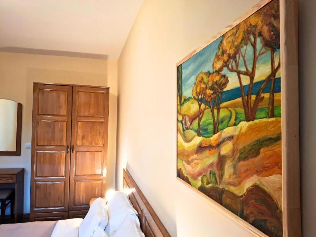 Une chambre à coucher avec un lit, une armoire en bois et un tableau représentant un paysage.